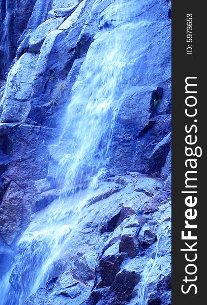 Waterfall over large rocks in blue color. Waterfall over large rocks in blue color.