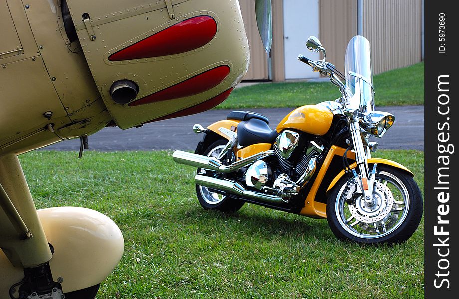 This is a shot of a custom motorcycle and front of an antique aircraft. This is a shot of a custom motorcycle and front of an antique aircraft.