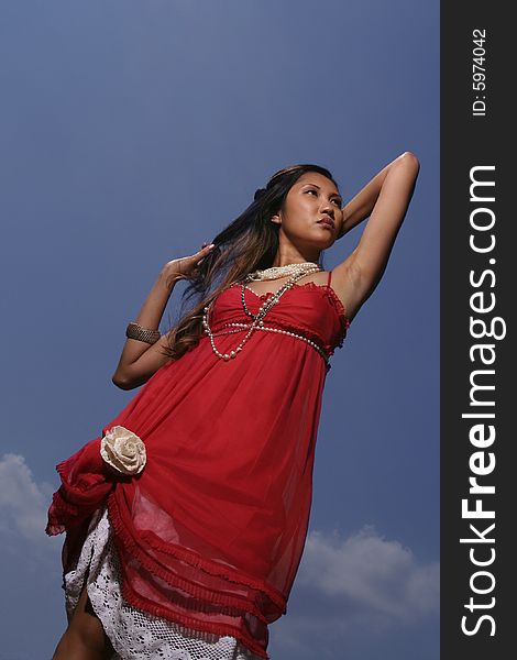 Filipino woman in red dress against blue sky. Filipino woman in red dress against blue sky