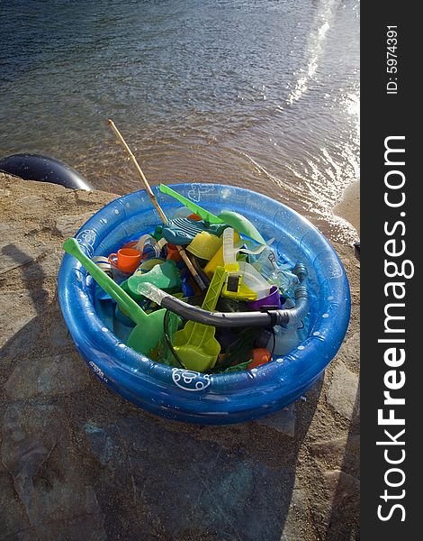 Beach toys collected in a blue plastic paddling pool at the end of the afternoon on the beach at Tamariu, Costa Brava, Catalonia, Spain. Beach toys collected in a blue plastic paddling pool at the end of the afternoon on the beach at Tamariu, Costa Brava, Catalonia, Spain