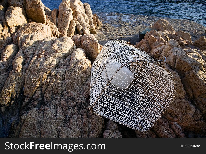 Lobster pot left on rocks by the boat dock at Tamariu Costa Brava, Catalonia, Spain. Lobster pot left on rocks by the boat dock at Tamariu Costa Brava, Catalonia, Spain