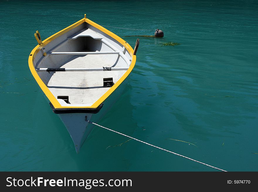 A yellow and white rowing boat on deep green water, plenty of copy space. A yellow and white rowing boat on deep green water, plenty of copy space