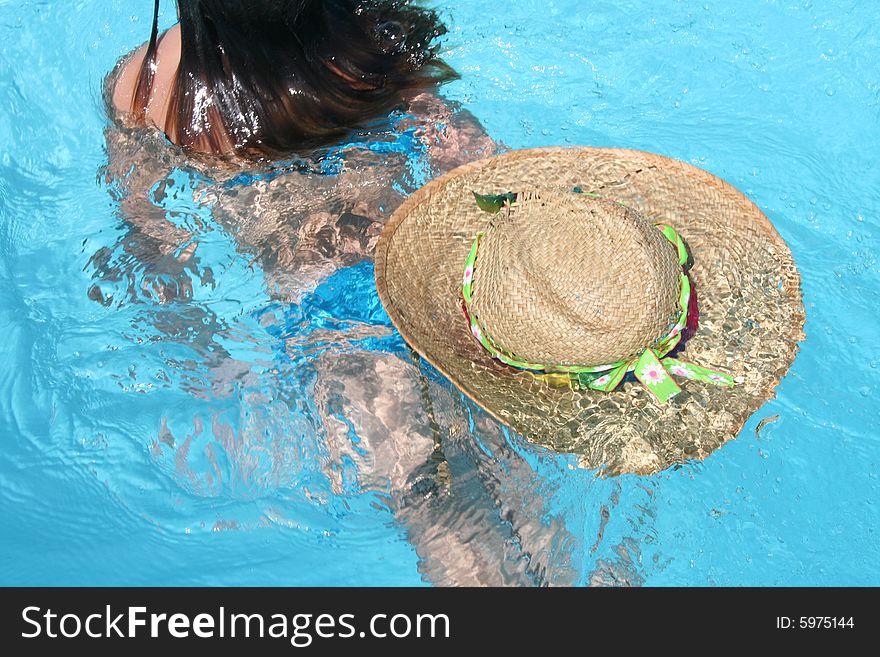 Girl swimming away with straw hat floating behind. Girl swimming away with straw hat floating behind.