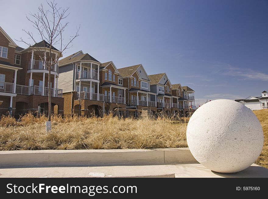 Concrete ball and row of new houses in the background located steps form the unionville beach ontario canada. Concrete ball and row of new houses in the background located steps form the unionville beach ontario canada