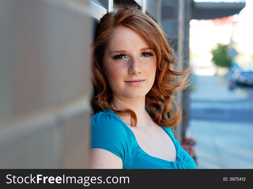 A young girl is standing with her back to a wall of bricks.  She is smiling at the camera.  Horizontally framed shot. A young girl is standing with her back to a wall of bricks.  She is smiling at the camera.  Horizontally framed shot.