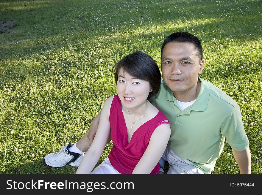 Smiling Couple Sitting on Grass - Horizontal