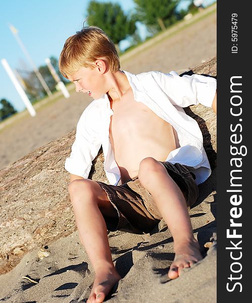 Boy Sitting In Sand On Beach - Vertical