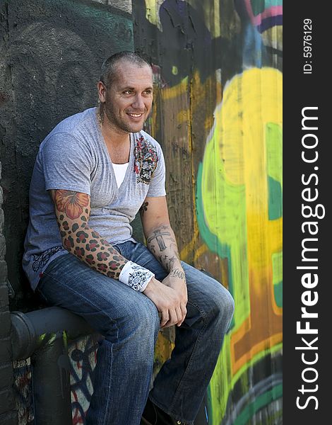 Handsome Male Fashion model posing by graffiti covered wall