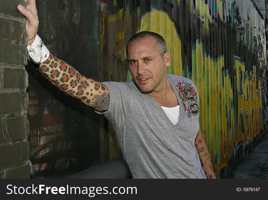 Handsome Male Fashion model posing by graffiti covered wall