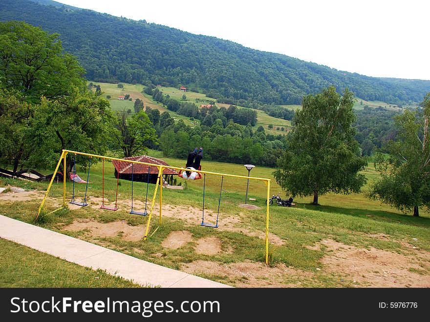 Adult man swinging on swing over rural landscape. Adult man swinging on swing over rural landscape