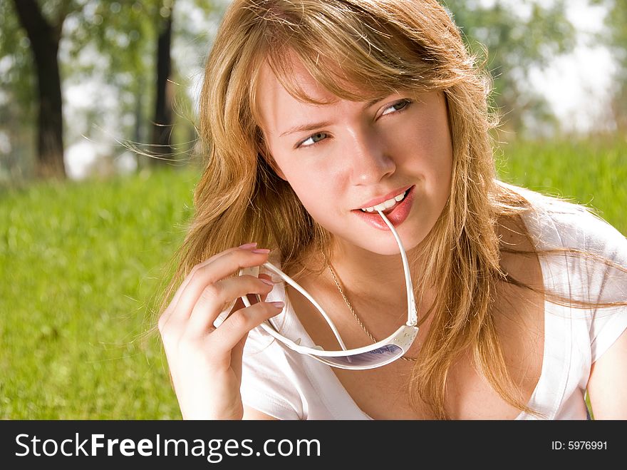 Thoughtful blond girl sitting on the grass in the park. Thoughtful blond girl sitting on the grass in the park