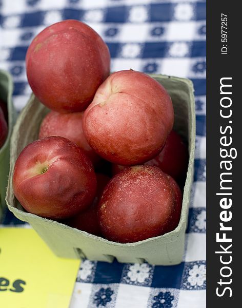 Sweet nectarines displayed on a white and blue checked cloth. Sweet nectarines displayed on a white and blue checked cloth.