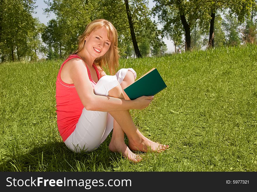 Pretty young girl reading a book outdoor