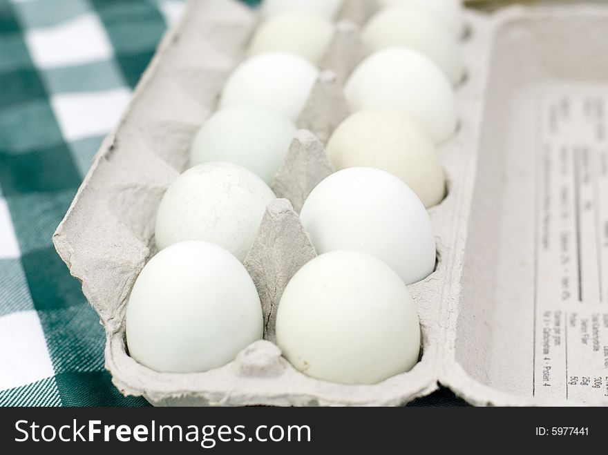 One dozen white eggs in an open gray carton. One dozen white eggs in an open gray carton.