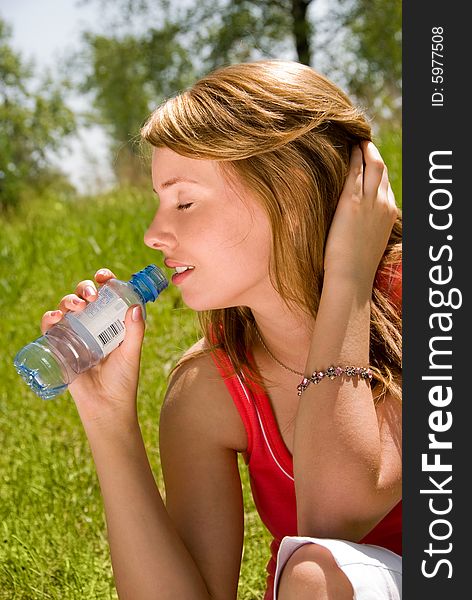 Young girl drinks water  in the park