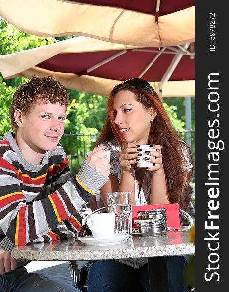Young couple drinking coffee in open-air cafe. Young couple drinking coffee in open-air cafe