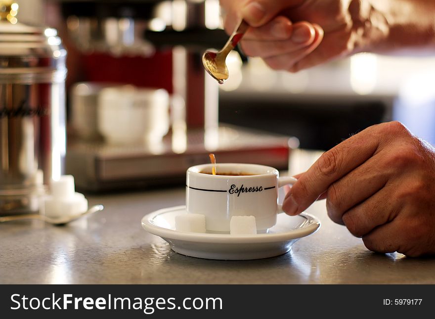 Close-up of a men putting sugar in an espresso coffee cup. Close-up of a men putting sugar in an espresso coffee cup