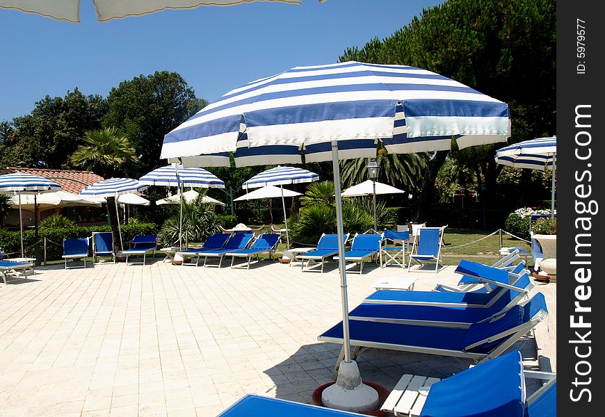 A beautiful shot of beach umbrellas and deck chairs in a solarium near a pool. A beautiful shot of beach umbrellas and deck chairs in a solarium near a pool