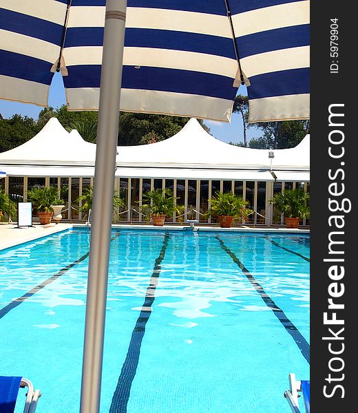 An original shot of a pool with a close up of a beach umbrella. An original shot of a pool with a close up of a beach umbrella
