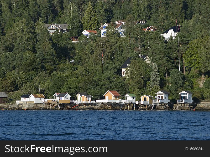 Traditional bathhouses on the coast of Norway with forest and homes in the background. Traditional bathhouses on the coast of Norway with forest and homes in the background.