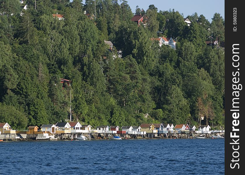 Traditional bathhouses on the coast of Norway with forest and homes in the background. Traditional bathhouses on the coast of Norway with forest and homes in the background.