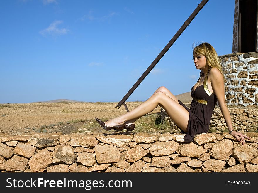 Young beautiful woman posing on a old windmill. Young beautiful woman posing on a old windmill