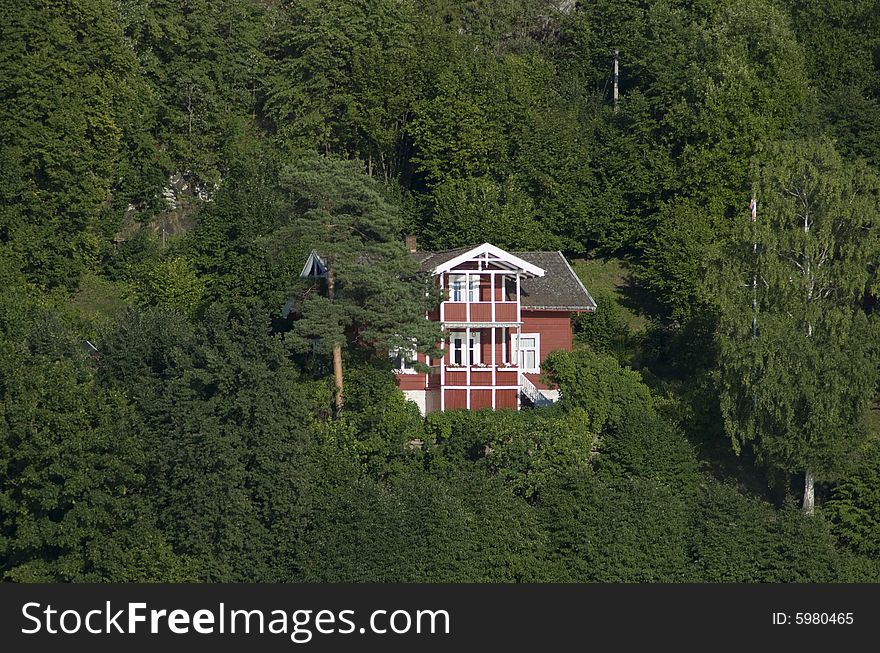 Old, traditional style red house among the trees in a green forest. Old, traditional style red house among the trees in a green forest.