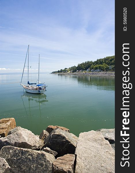 Sail boat on a calm river surrounded by a mountain