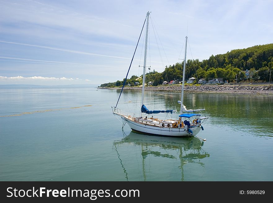 Sail boat on a calm river surrounded by a mountain