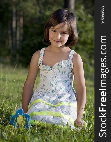 Lovely little girl sits on green grass