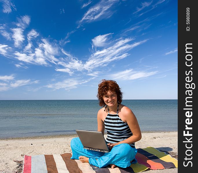 Girl sitting with laptop on the sea coast. Girl sitting with laptop on the sea coast