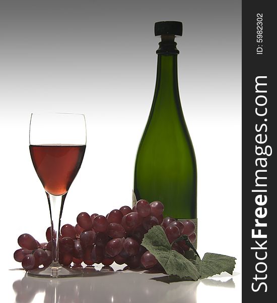 Wine in a glass with wine bottle and grapes