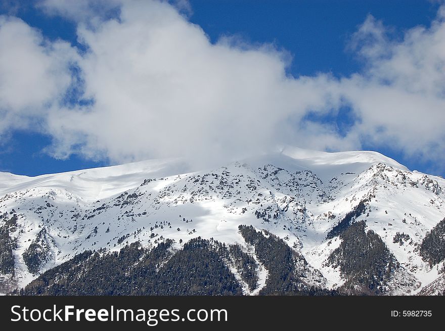 snowy mountain peak covered by white winter cloud. snowy mountain peak covered by white winter cloud