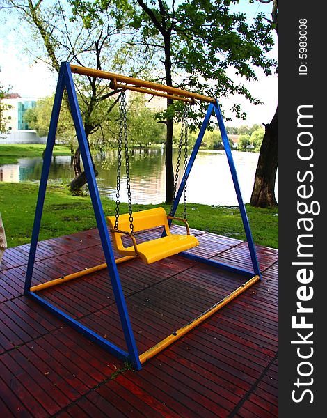 Bright yellow-blue children's swings in the park. Bright yellow-blue children's swings in the park