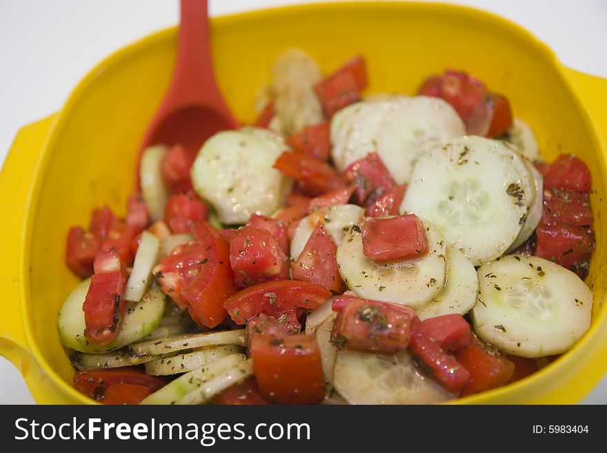 Cucumber and Tomato Salad in a yellow bowl with red spoon