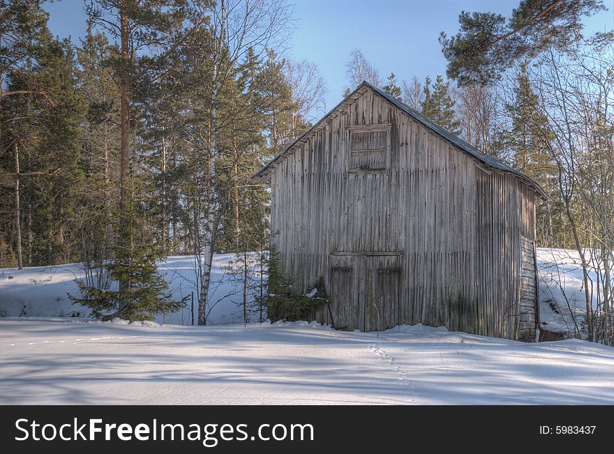 An old, bleached barn surrounded by a snowy forest. An old, bleached barn surrounded by a snowy forest.