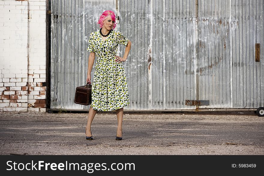 Woman with pink hair in an alley with small suitcase. Woman with pink hair in an alley with small suitcase