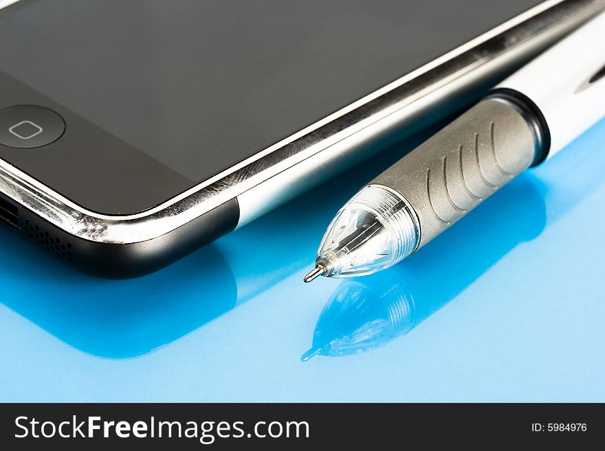 Pen and mobile phone on blue background
