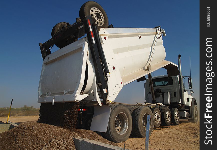 Dump truck backed up against foundation dumping dirt. Horizontally framed shot. Dump truck backed up against foundation dumping dirt. Horizontally framed shot.