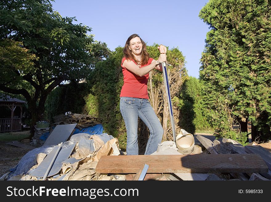 Woman laughing as she stands in a pile of rubble with a sword. Horizontally framed photograph. Woman laughing as she stands in a pile of rubble with a sword. Horizontally framed photograph
