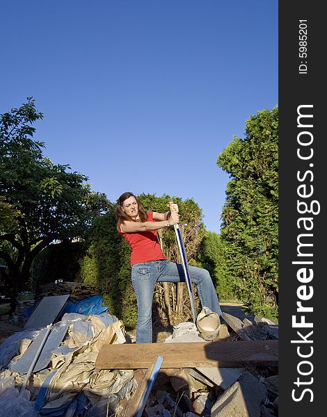 Woman looking frustrated as she stands in a pile of rubble with a sword. Vertically framed photograph. Woman looking frustrated as she stands in a pile of rubble with a sword. Vertically framed photograph