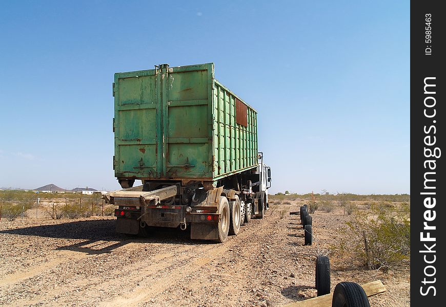 Green garbage truck on a desert road. Horizontally framed shot. Green garbage truck on a desert road. Horizontally framed shot.