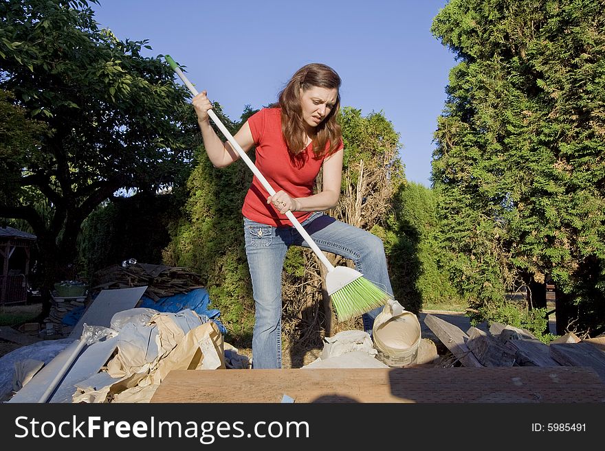 Woman going through a pile of garbage with a broom. Horizontally framed photograph. Woman going through a pile of garbage with a broom. Horizontally framed photograph.