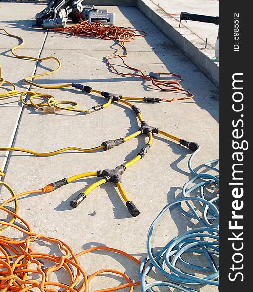 Snake-like coils of electrical cable lying on a concrete foundation slab. Vertically framed shot.