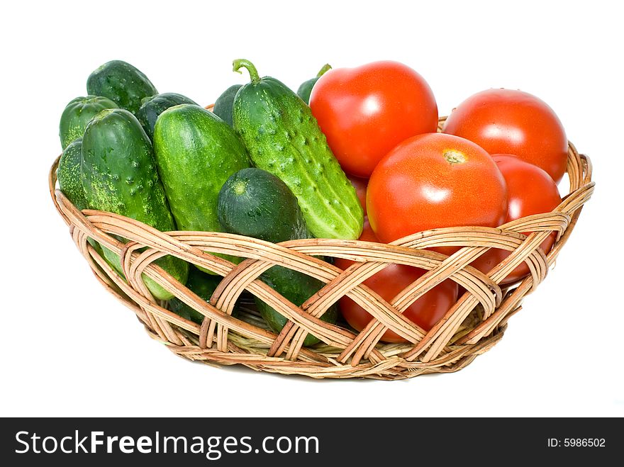 Wicker basket with some tomatoes and cucumbers isolated on the white background