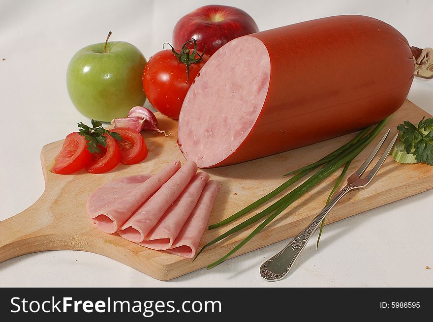 Ham in slices with vegetables on the bread board