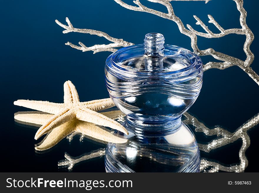 Blue bottle of perfume with starfish and corals