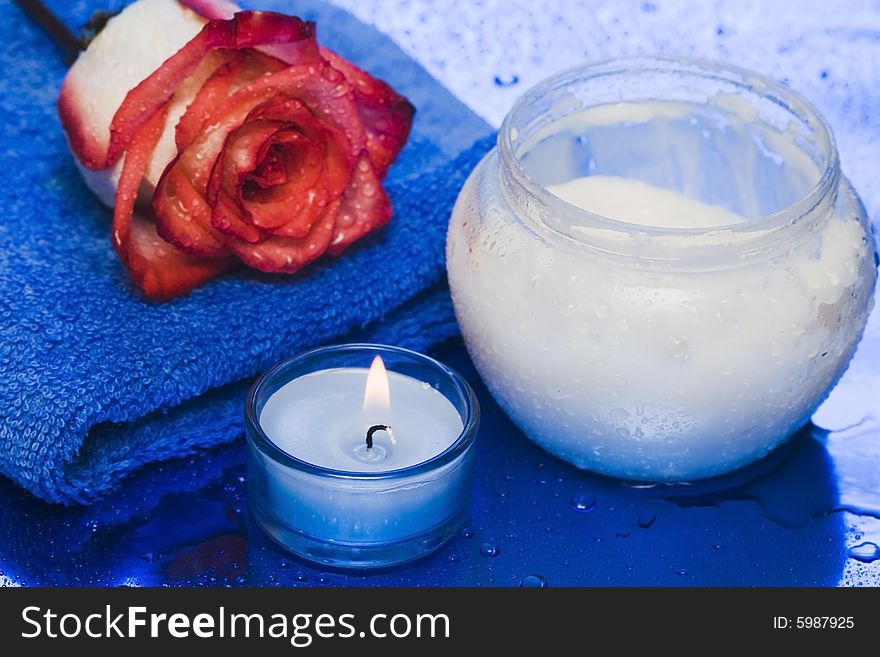 Cream, candle with rose on blue background