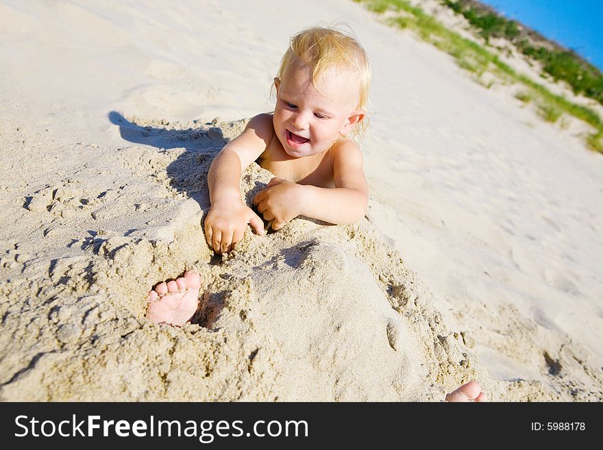 Young girl buried in the sand smiling at camera. Young girl buried in the sand smiling at camera