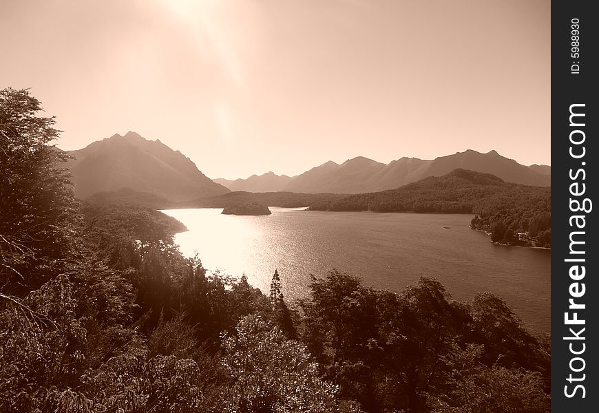 Image of lake in lake district bariloche, argentina. sepia colors, late in the afternoon. branches in front, mountains/hills in the back. Image of lake in lake district bariloche, argentina. sepia colors, late in the afternoon. branches in front, mountains/hills in the back